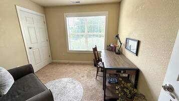 A room with a desk, chair, and a small rug.