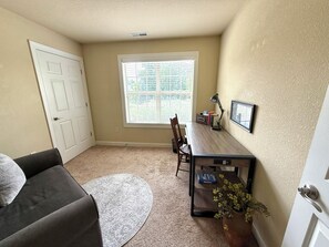 A room with a desk, chair, and a small rug.