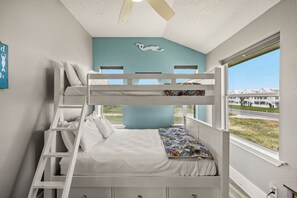 A bunk bed with a ladder, a window with a view of houses, and a ceiling fan. - Galveston Beachfront Home with Gulf Views, Beach Access and Waterfront Deck (Galveston)