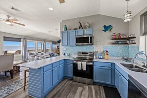 A modern kitchen with blue cabinets, a stainless steel oven, and a large island. - Galveston Beachfront Home with Gulf Views, Beach Access and Waterfront Deck (Galveston)