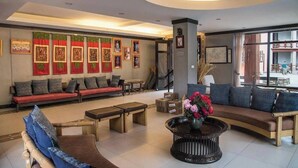A modern hotel lobby with a sofa, coffee table, and artwork on the walls. - Haven Resort Paro (Paro)