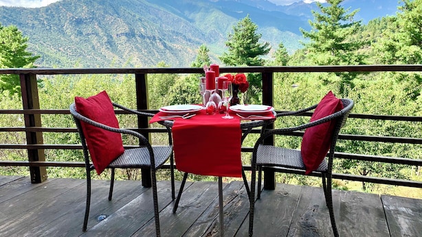 A dining table with red tablecloth and chairs, set against a mountain backdrop. - Haven Resort Paro (Paro)