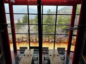 A dining area with tables and chairs, large windows with a view of a wooden deck and mountains. - Haven Resort Paro (Paro)