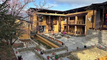A courtyard with a building featuring a balcony and a stone wall.