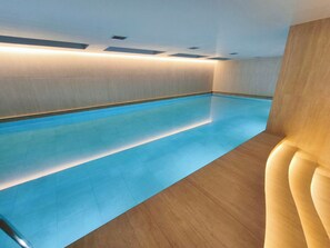 Une piscine dotée d’un plancher en bois et d’un mur de couleur claire.