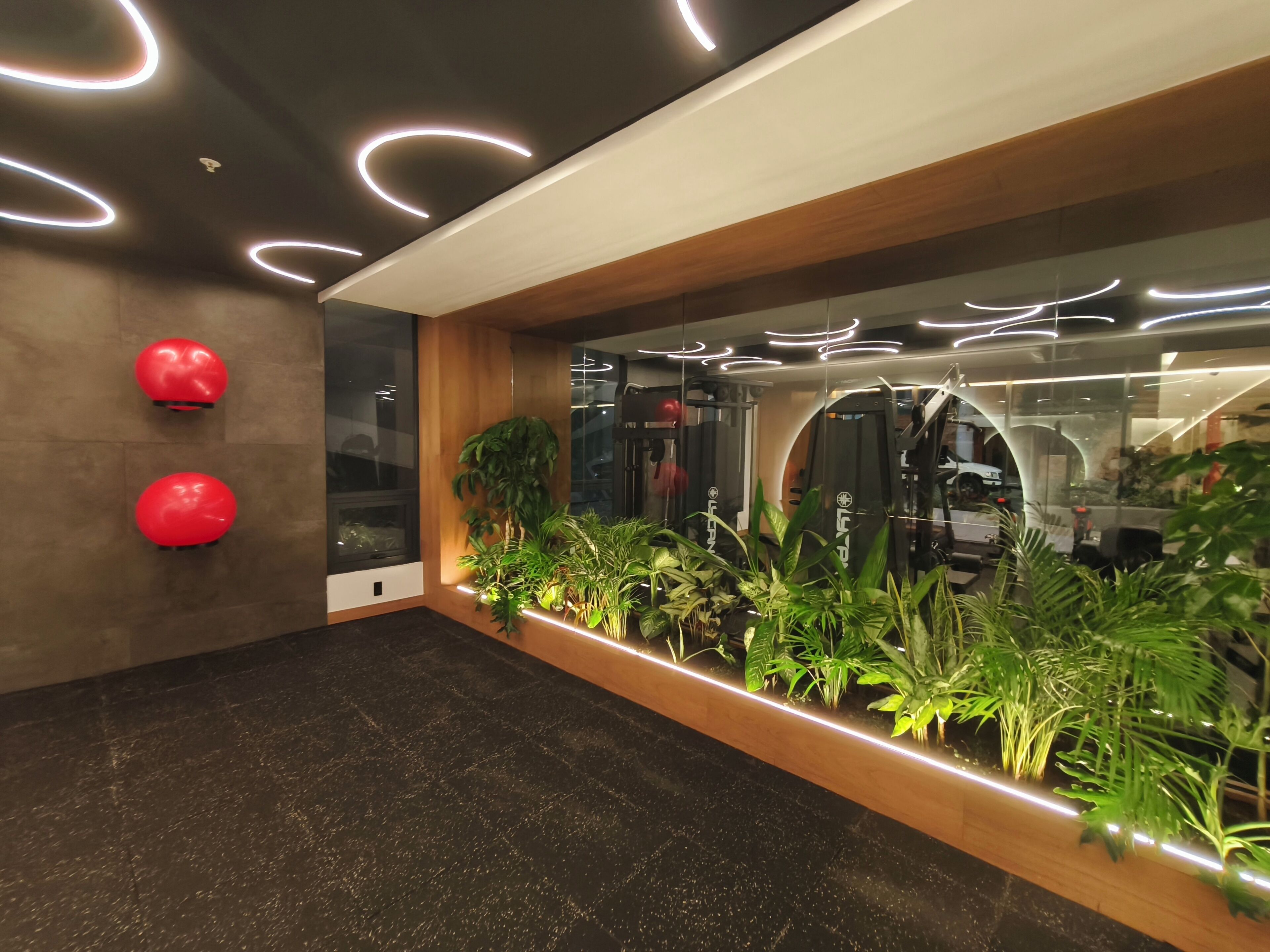 A modern interior with a dark floor, wooden accents, and a long planter with green plants.