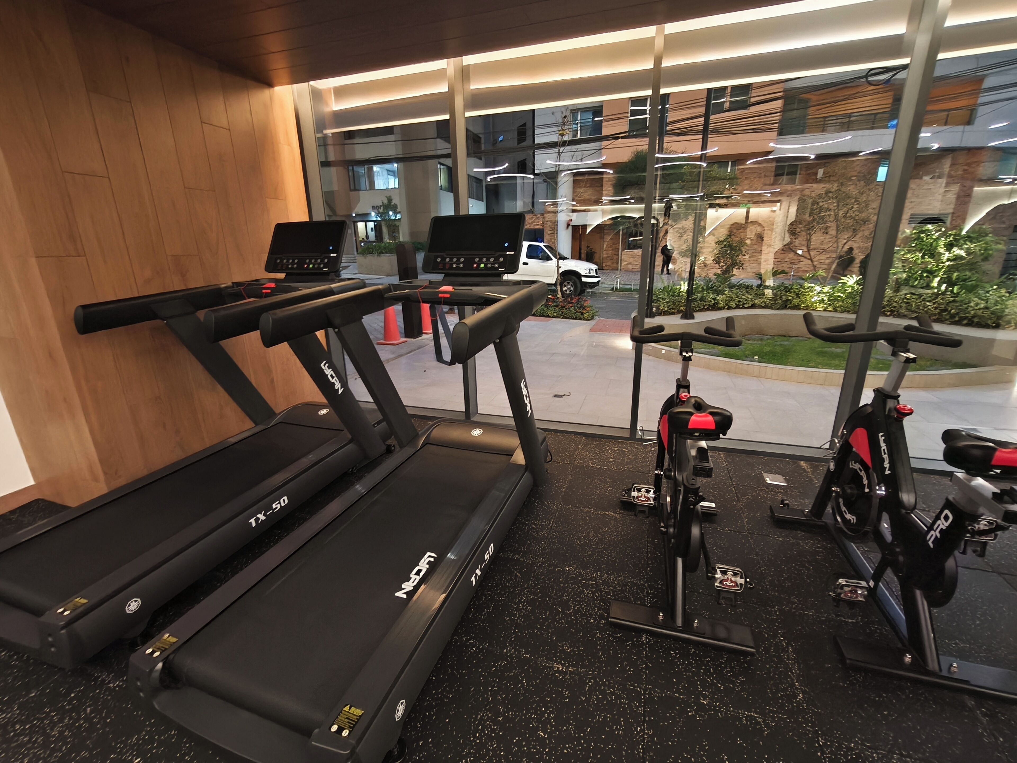 Un gimnasio con cintas de correr, una bicicleta estática y vistas al exterior.