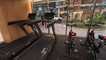 Un gimnasio con cintas de correr, una bicicleta estática y vistas al exterior.