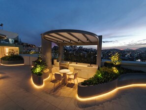 Un espace extérieur aménagé avec une pergola, des chaises et des jardinières.