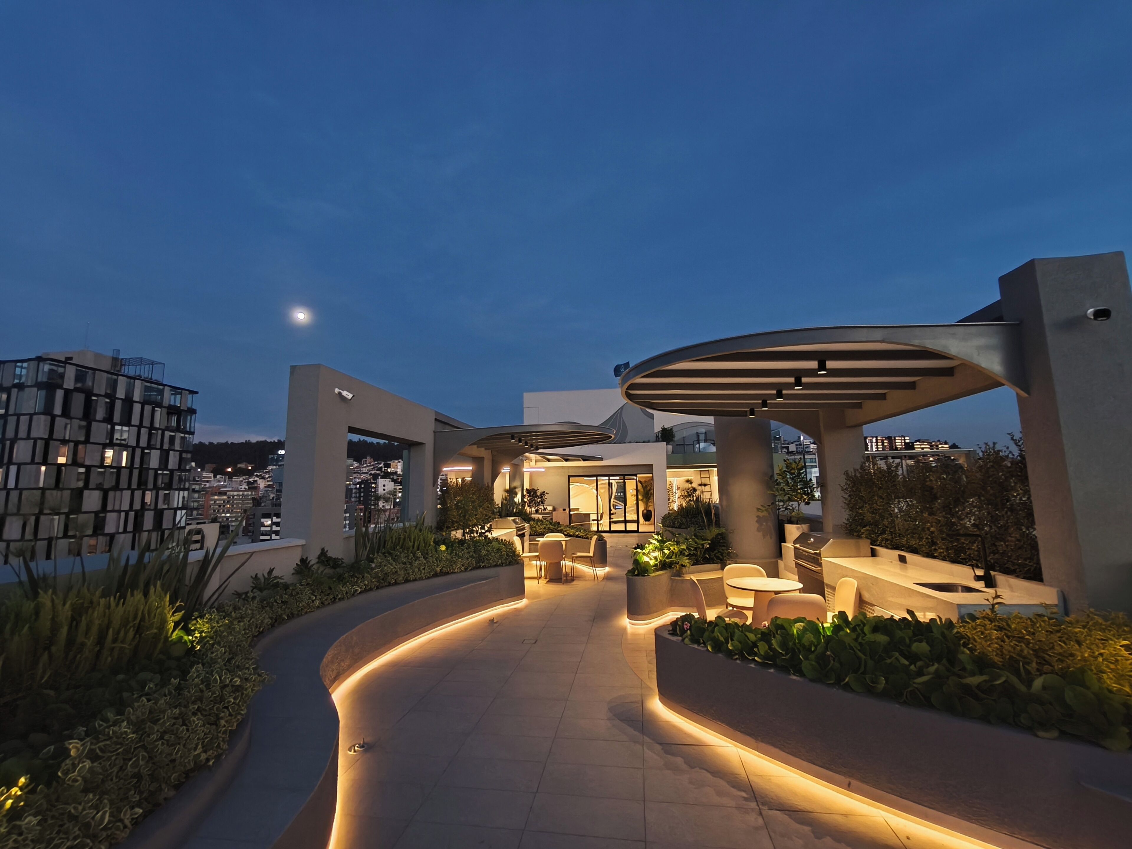 A modern outdoor area with a curved pathway, seating, and planters.