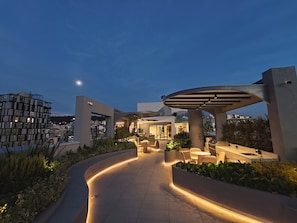 Un espacio exterior moderno con un sendero curvo, asientos y jardineras.