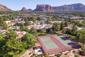 Ein Wohngebiet mit Tennisplatz, Schwimmbad und Bergelandschaft im Hintergrund.