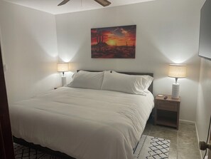 Ein Schlafzimmer mit einem Bett, zwei Nachttischlampen, einem Nachttisch, einem Bild an der Wand und einem gemusterten Teppich.