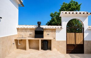 An outdoor kitchen area with a grill, sink, and storage space. - Gorgeous home in Iznajar (Iznajar)