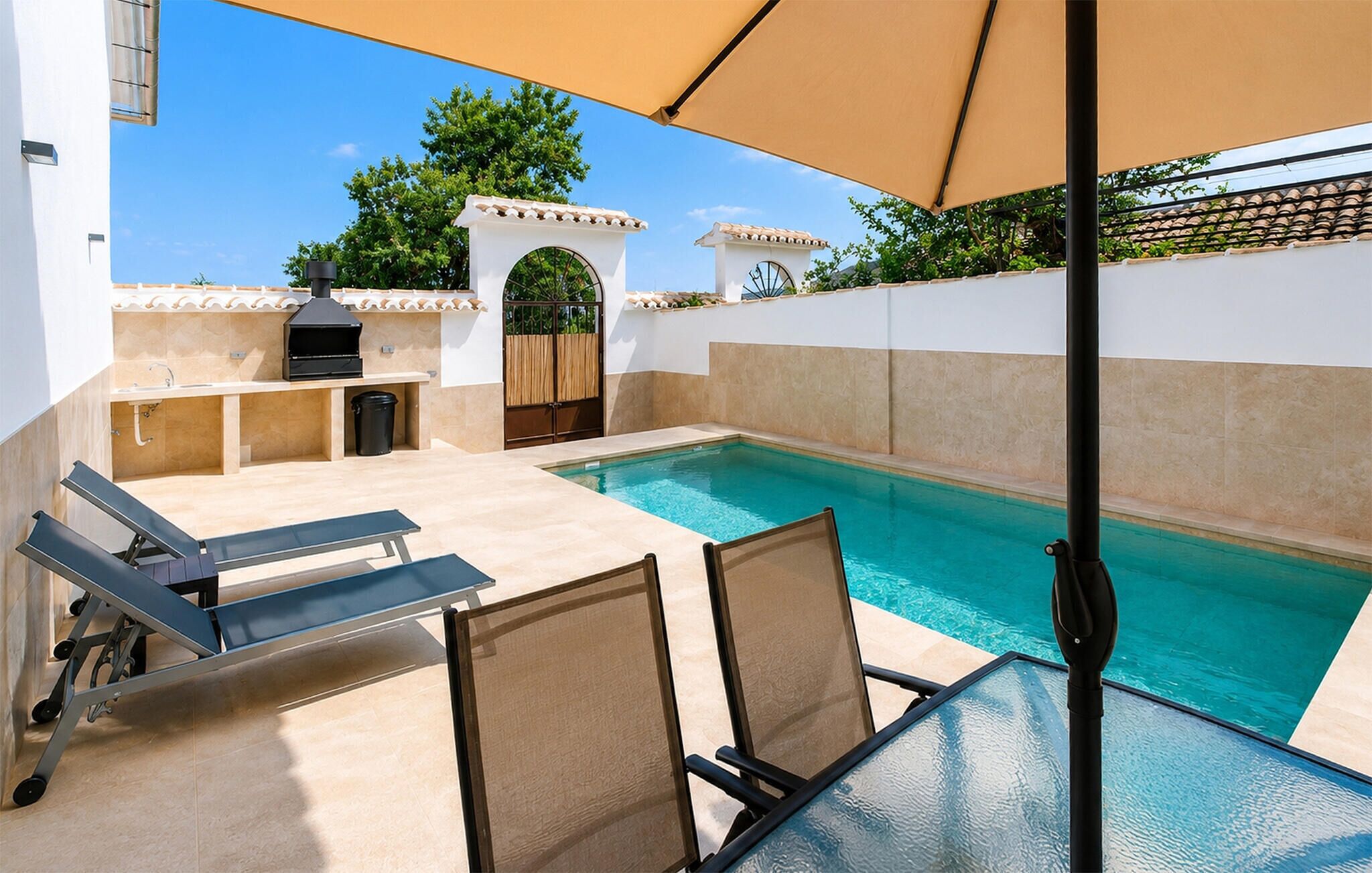 An outdoor pool area with a barbecue setup, lounge chairs, and a pergola providing shade.