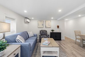 Un salon moderne comprenant un canapé, un fauteuil, une table basse et un coin repas avec une table et des chaises.