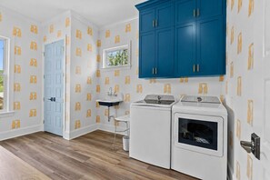 Ein Waschraum mit einem blauen Schrank, einem Waschbecken und zwei Waschmaschinen.