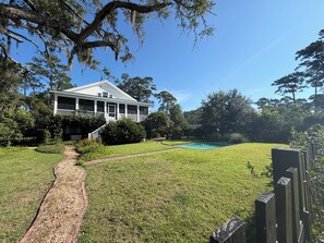 A house with a covered porch, a swimming pool, and a well-maintained lawn. - DEEP WATER DOCK, PRIVATE POOL, two screened porches for dining and game watched. (Midway)
