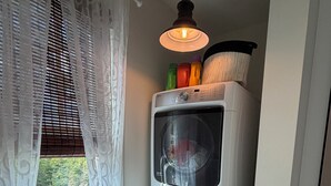 A laundry room with a washing machine and dryer stacked on top of each other, a step stool, and a hanging light fixture. - DEEP WATER DOCK, PRIVATE POOL (Midway)