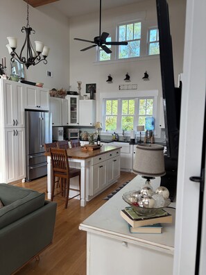 A modern kitchen with white cabinetry, a stainless steel refrigerator, a wooden dining table, and a ceiling fan. - DEEP WATER DOCK, PRIVATE POOL, two screened porches for dining and game watched. (Midway)