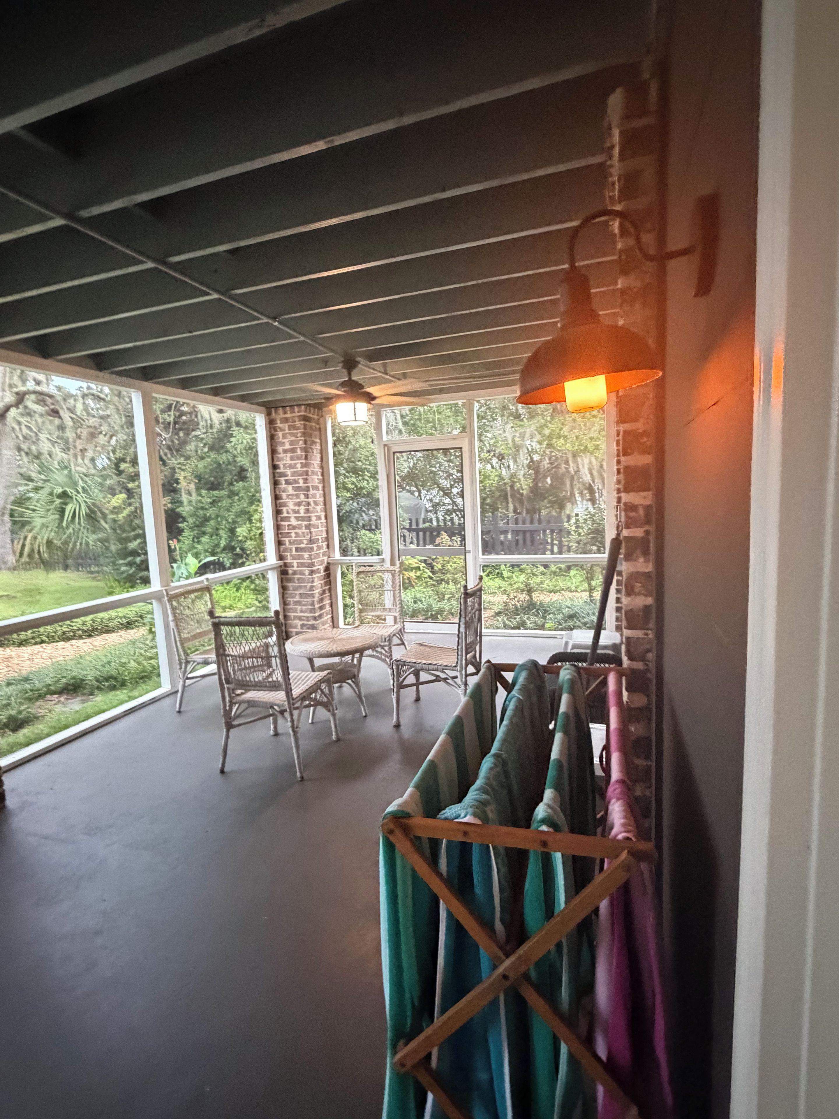 A covered outdoor seating area with wicker furniture and a hanging rack.