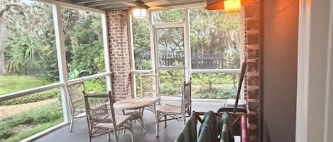A covered outdoor seating area with wicker furniture and a hanging rack.