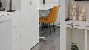 Eine moderne Küche mit weißen Schränken, einer Kaffeemaschine und einem Essbereich mit Tisch und Stühlen.