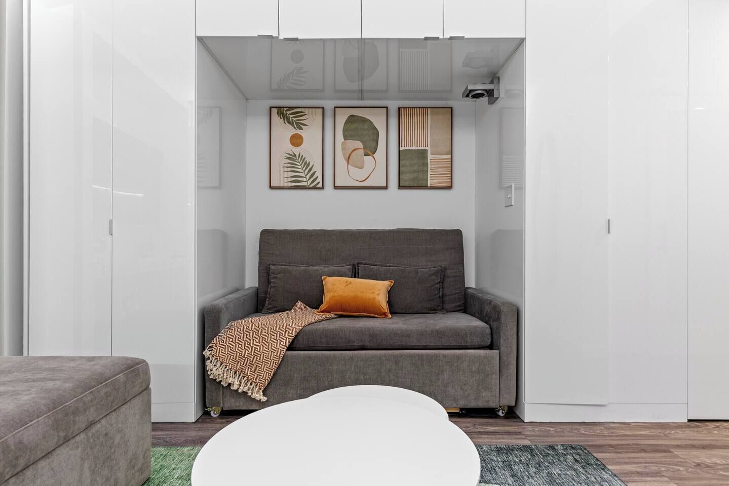 A modern living room with a grey sofa, a patterned throw blanket, and a white coffee table.