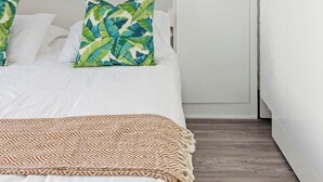 Ein Schlafzimmer mit einem Bett, Kissen, einer Decke und einem Kleiderschrank.