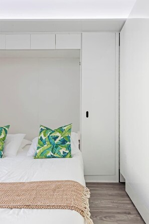 Ein Schlafzimmer mit einem Bett, Kissen, einer Decke und einem Kleiderschrank.
