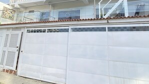 Ein zweistöckiges Gebäude mit weißer Fassade, einem Balkon im oberen Geschoss und einer Garagentür.