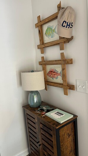 A wall-mounted wooden fish display with a lamp and a book on a wooden cabinet. - Moss & Marsh | Marshfront Views, Pool & Island Charm (Saint Simons Island)