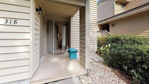 A residential building with a number '318' on the side, a covered porch, and a small blue bench. - Moss & Marsh | Marshfront Views, Pool & Island Charm (Saint Simons Island)