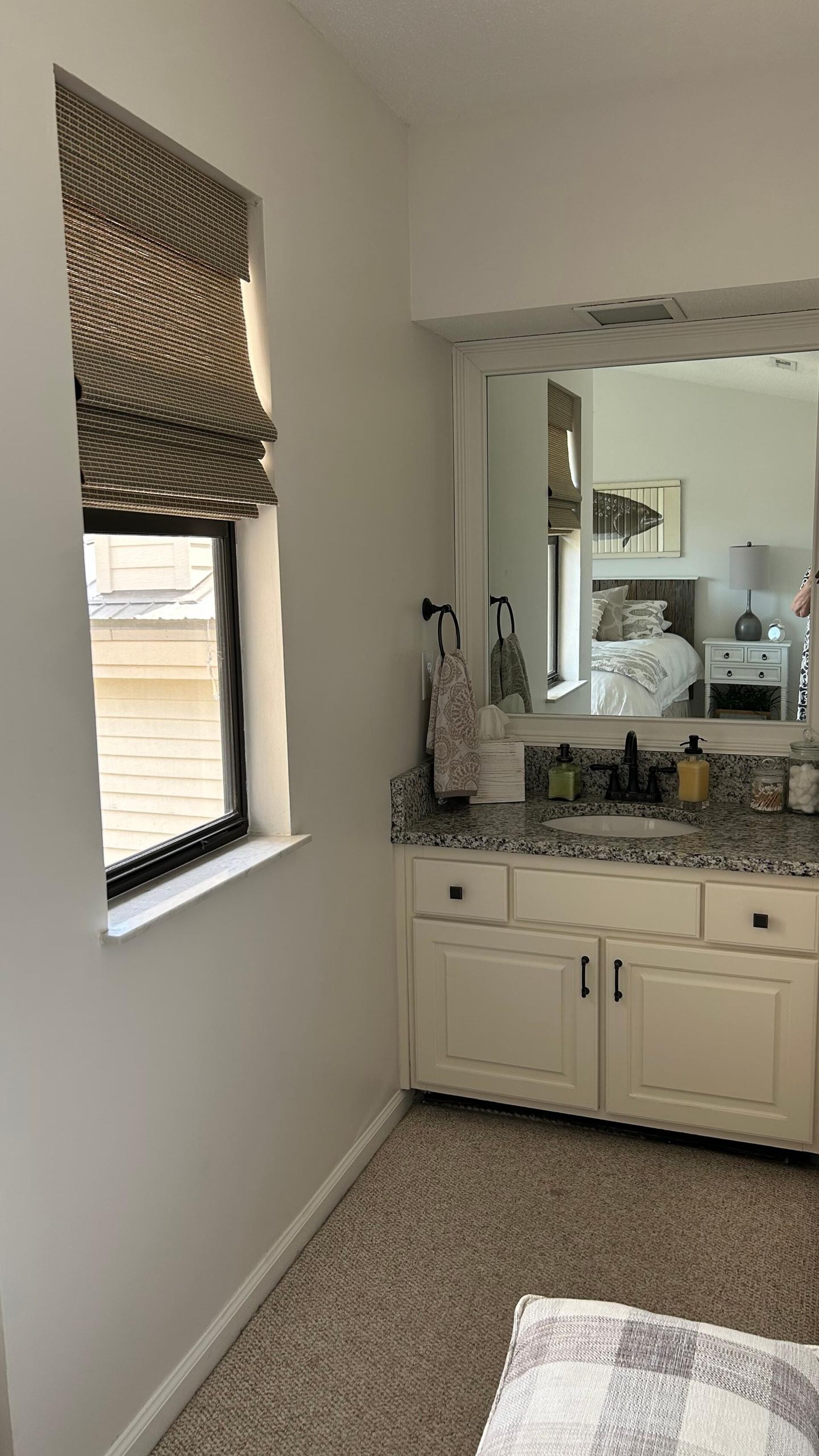 Un baño con ventana, lavamanos, espejo y mueble.