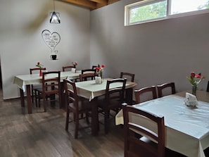 Un comedor con mesas y sillas, un adorno en forma de corazón en la pared, y una ventana.