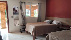 Een hotelkamer met twee bedden, een stoel en een raam met gordijnen.