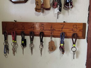 A wall-mounted key rack with numbered hooks holding keys and keychains. - Posada Doña Celes (Urique)
