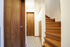 A wooden staircase with a geometric patterned floor leading to a door.