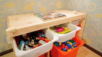 A child's play area with a wooden shelf and two bins filled with toys.