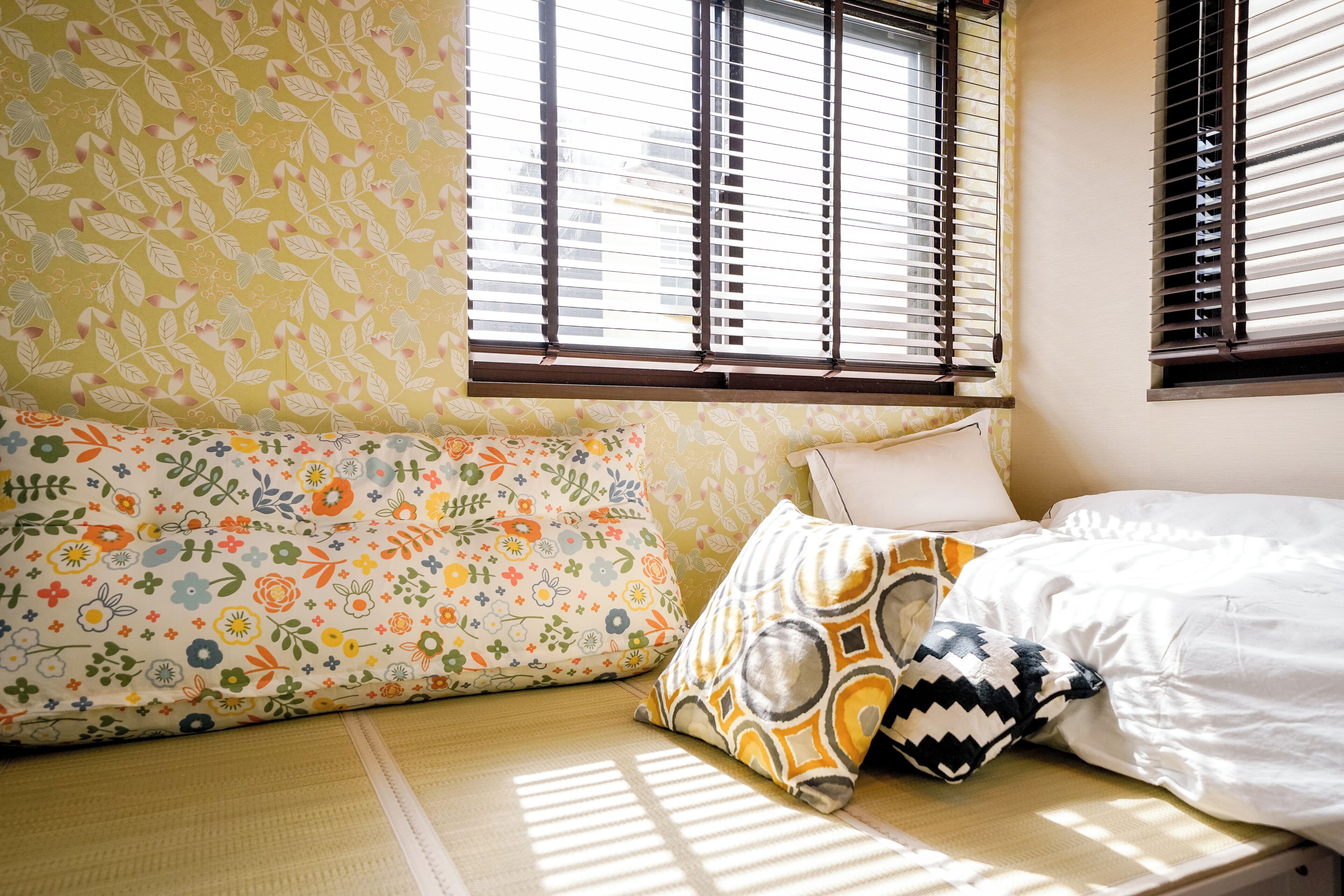 A room with a bed, a sofa, and a window with blinds.