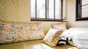 A room with a bed, a sofa, and a window with blinds.