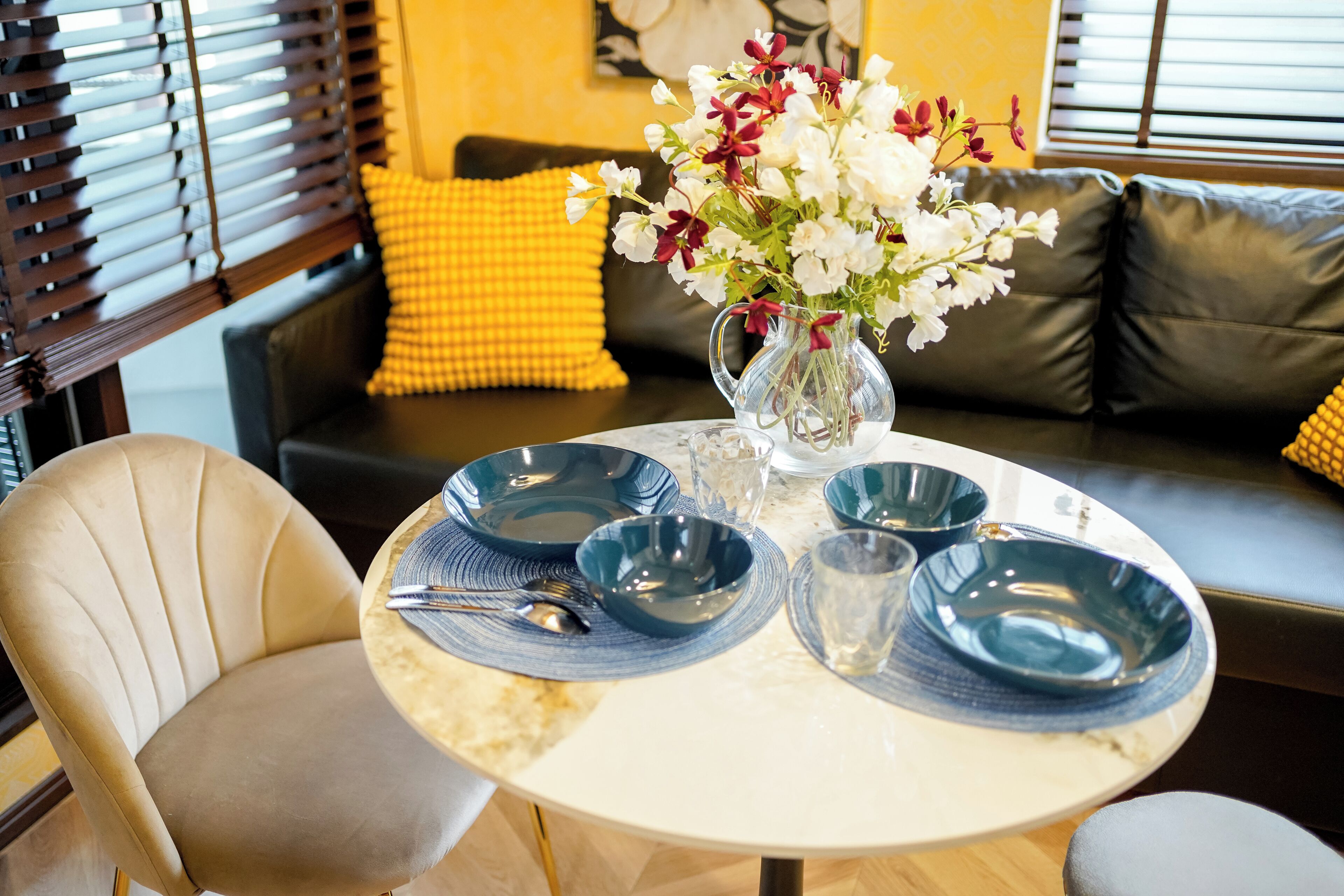 A dining table with blue plates, a vase with flowers, and a chair.