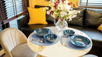 A dining table with blue plates, a vase with flowers, and a chair.