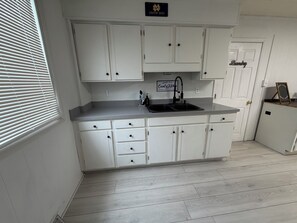 A kitchen with white cabinets, a black sink, and a sign above the sink that reads 'Country Kitchen.' - The All-Star Stay (South Bend)
