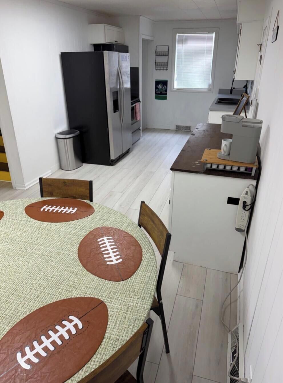 A compact kitchen with a refrigerator, a coffee maker, and a window.