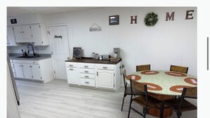 Eine Küche mit weißen Schränken, einem Esstisch mit Tischdecke zum Thema Fußball und einem Schild mit der Aufschrift 'HOME' an der Wand.