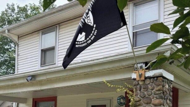 Ein zweistöckiges Haus mit einer Stein Säule und einer Flagge.