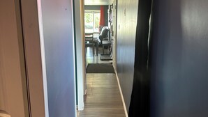 A hallway with a wooden floor, a door on the left, and a black curtain on the right. - 2 bedroom home in Fort Frances Ontario (Fort Frances)