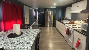 A modern kitchen with stainless steel appliances, a dining area with a patterned tablecloth, and red curtains. - 2 bedroom home in Fort Frances Ontario (Fort Frances)