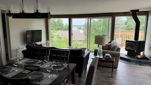 Un salon comprenant un canapé, une table à manger dressée pour quatre personnes, un téléviseur et une cheminée.